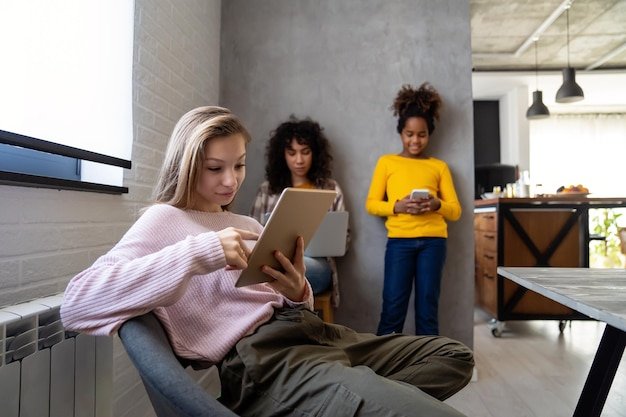 A diverse group of people using virtual closet apps on their tablets and smartphones, all smiling and engaged. Background elements include a modern office space and a cozy living room.